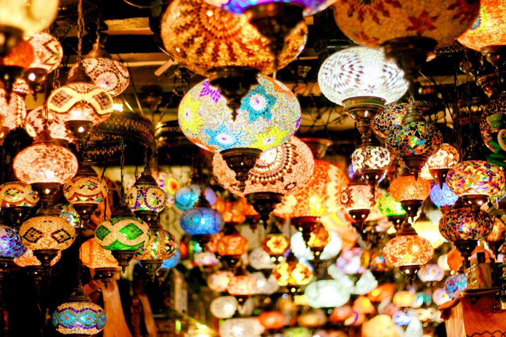 Vibrantly illuminated hanging lanterns in a bustling market create a warm and colorful atmosphere.