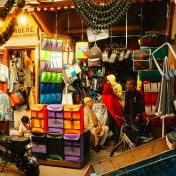 Colorful market stall in Marrakech medina displaying textiles and crafts, capturing vibrant local culture.